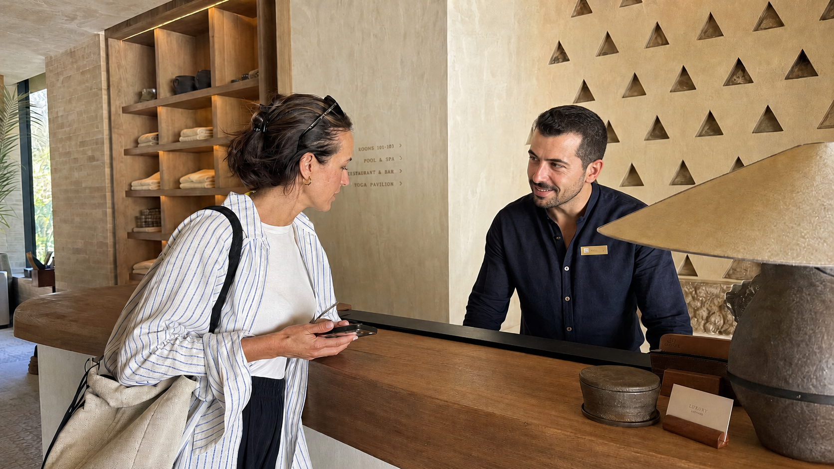 Empleado de recepción atendiendo a una huésped en el mostrador de un hotel wellness